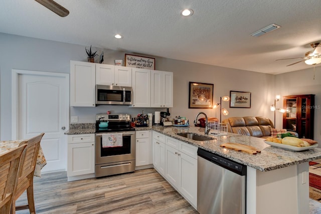 5005 Joseph St, Hastings, FL 32145 - kitchen with appliances with stainless steel finishes, a ceiling fan, a peninsula, open floor plan, and white cabinets