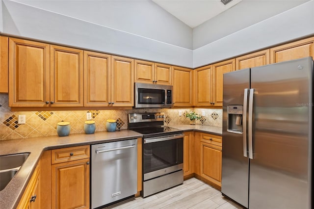 1636 Areca Palm Dr, Port Orange, FL 32128 - kitchen with stainless steel appliances, tasteful backsplash, brown cabinets, vaulted ceiling, and light wood-style flooring