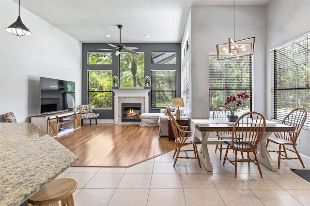 6710 Merryvale Ln, Port Orange, FL 32128 - dining area featuring a fireplace, ceiling fan, light tile patterned floors, a chandelier, and a high ceiling