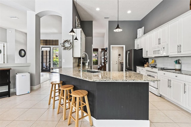 6710 Merryvale Ln, Port Orange, FL 32128 - kitchen with white appliances, light tile patterned floors, tasteful backsplash, a kitchen bar, and light stone counters