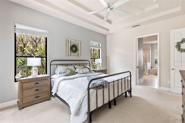 6710 Merryvale Ln, Port Orange, FL 32128 - bedroom featuring a tray ceiling, light colored carpet, connected bathroom, and a ceiling fan