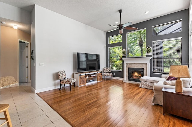 6710 Merryvale Ln, Port Orange, FL 32128 - living room with a tile fireplace, a ceiling fan, a high ceiling, a textured ceiling, and light tile patterned flooring