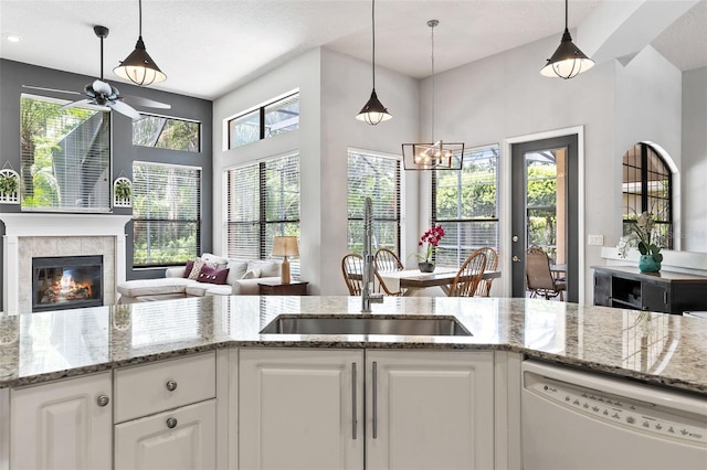 6710 Merryvale Ln, Port Orange, FL 32128 - kitchen with dishwasher, ceiling fan, a tiled fireplace, light stone countertops, and white cabinetry
