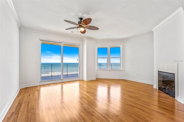 2515 S Atlantic Ave Unit 507, Daytona Beach, FL 32118 - unfurnished living room with light wood finished floors, a textured ceiling, a fireplace, ceiling fan, and crown molding