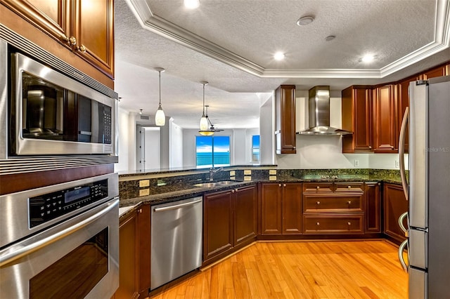 2515 S Atlantic Ave Unit 507, Daytona Beach, FL 32118 - kitchen featuring appliances with stainless steel finishes, wall chimney range hood, a tray ceiling, light wood finished floors, and a textured ceiling