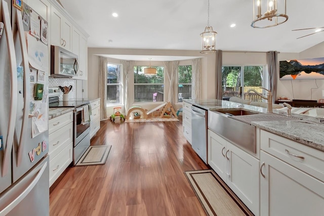 1522 E Silver Hammock, Deland, FL 32720 - kitchen featuring stainless steel appliances, wood finished floors, white cabinets, hanging light fixtures, and tasteful backsplash