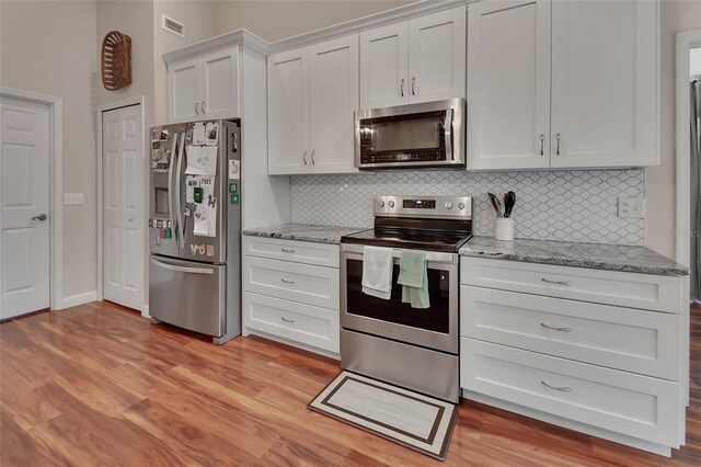 1522 E Silver Hammock, Deland, FL 32720 - kitchen with appliances with stainless steel finishes, tasteful backsplash, light wood finished floors, and light stone counters