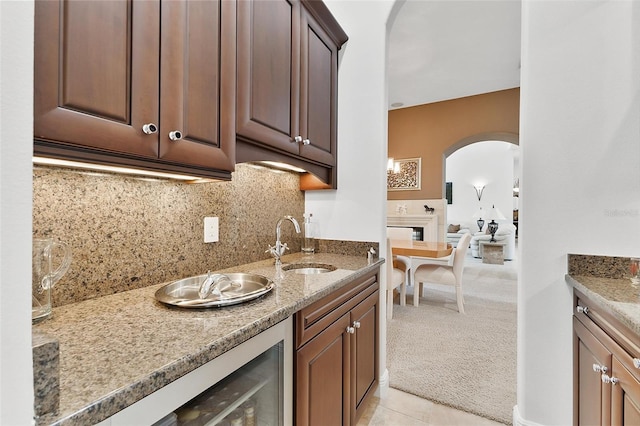 12812 Jacob Grace Ct, Windermere, FL 34786 - kitchen featuring arched walkways, light colored carpet, tasteful backsplash, dark brown cabinets, and light stone counters