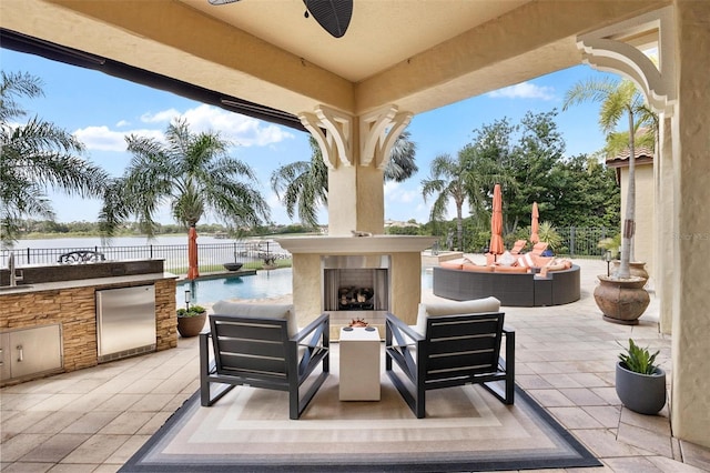 12812 Jacob Grace Ct, Windermere, FL 34786 - view of patio / terrace featuring an outdoor living space with a fireplace, a water view, exterior kitchen, and ceiling fan