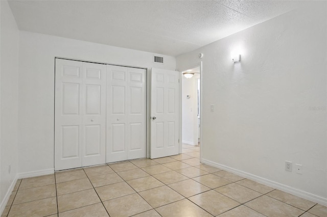 415 N Halifax Ave Unit 109, Daytona Beach, FL 32118 - unfurnished bedroom featuring a closet, light tile patterned floors, and a textured ceiling