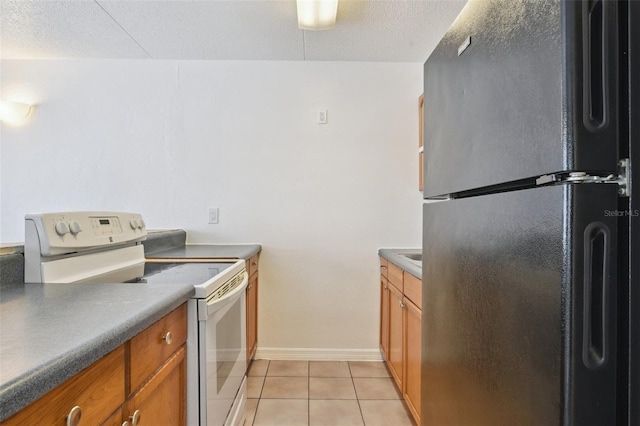 415 N Halifax Ave Unit 109, Daytona Beach, FL 32118 - kitchen featuring freestanding refrigerator, white range with electric cooktop, brown cabinets, light tile patterned floors, and a textured ceiling