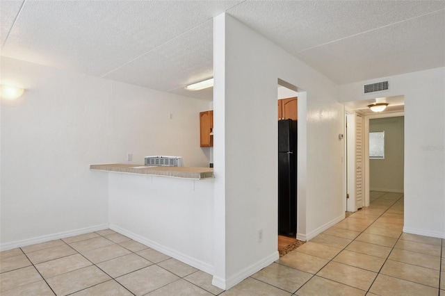 415 N Halifax Ave Unit 109, Daytona Beach, FL 32118 - kitchen with light countertops, freestanding refrigerator, light tile patterned floors, a textured ceiling, and brown cabinets