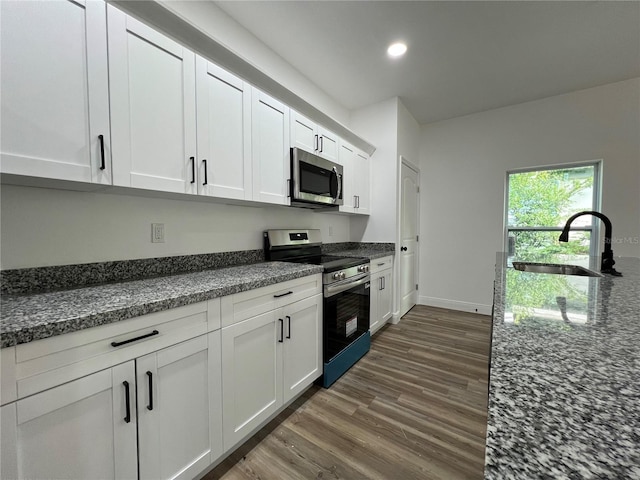 1510 Granada Ave, Daytona Beach, FL 32117 - kitchen with appliances with stainless steel finishes, dark wood-style flooring, recessed lighting, white cabinetry, and dark stone counters