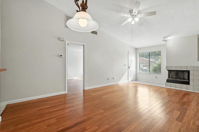1512 Heritage Ln, Daytona Beach, FL 32117 - unfurnished living room with a textured ceiling, a ceiling fan, wood finished floors, and a tile fireplace