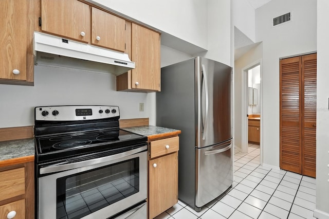1512 Heritage Ln, Daytona Beach, FL 32117 - kitchen with stainless steel appliances, under cabinet range hood, light tile patterned floors, and dark countertops