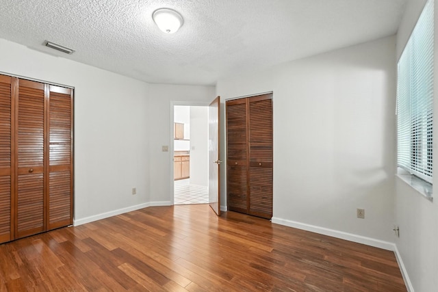 1512 Heritage Ln, Daytona Beach, FL 32117 - unfurnished bedroom featuring wood finished floors, a textured ceiling, and multiple closets