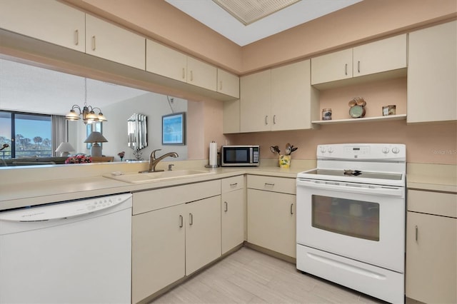 kitchen featuring a chandelier, decorative light fixtures, kitchen peninsula, white appliances, and sink