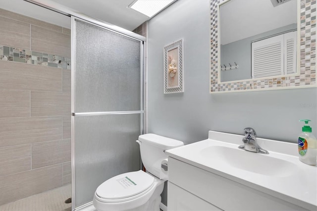 bathroom featuring a shower with shower door, vanity with extensive cabinet space, and toilet