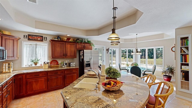 kitchen featuring pendant lighting, sink, a kitchen island with sink, stainless steel appliances, and a raised ceiling