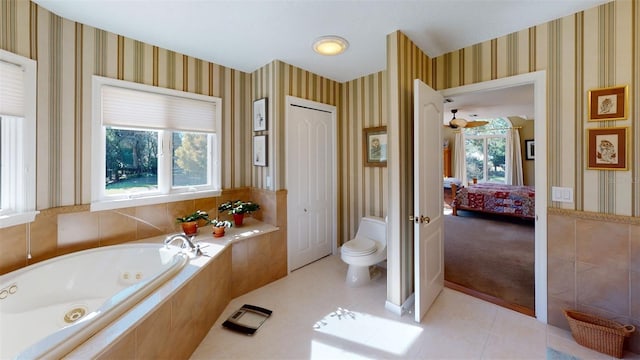 bathroom with a relaxing tiled tub, tile patterned floors, and toilet