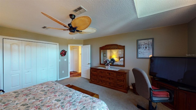 carpeted bedroom with ceiling fan, a closet, and a textured ceiling