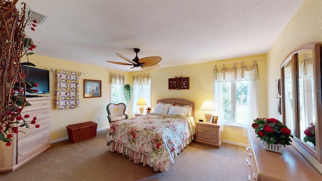 carpeted bedroom with ceiling fan and a textured ceiling