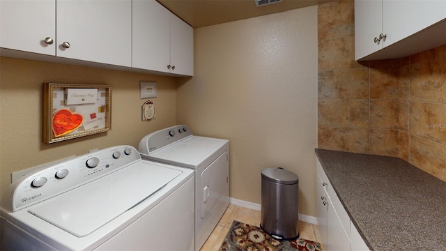 washroom featuring light tile patterned floors, washer and clothes dryer, and cabinets