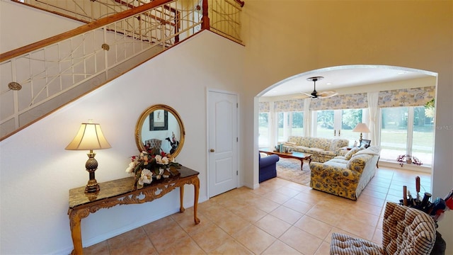 living room featuring ceiling fan, tile patterned flooring, and a towering ceiling