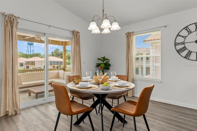 dining room featuring a notable chandelier, plenty of natural light, vaulted ceiling, and light wood-type flooring