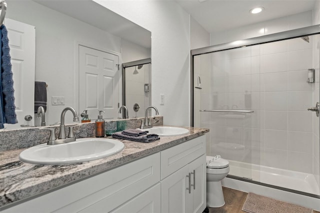 bathroom with hardwood / wood-style flooring, vanity, an enclosed shower, and toilet