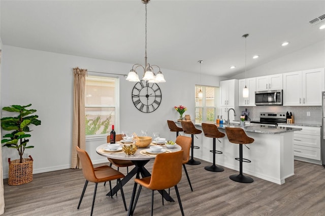 dining area with vaulted ceiling, sink, and hardwood / wood-style floors