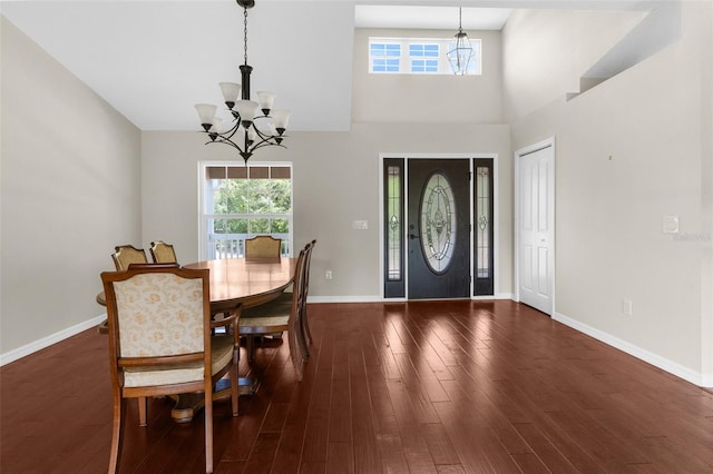 dining area featuring dark wood-type flooring, a high ceiling, and a notable chandelier