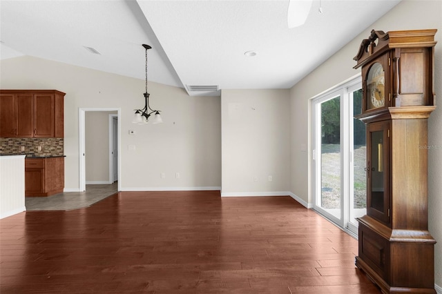 unfurnished living room with lofted ceiling, dark hardwood / wood-style floors, and ceiling fan with notable chandelier