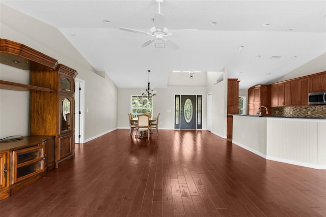 unfurnished living room with lofted ceiling, sink, ceiling fan with notable chandelier, and dark wood-type flooring