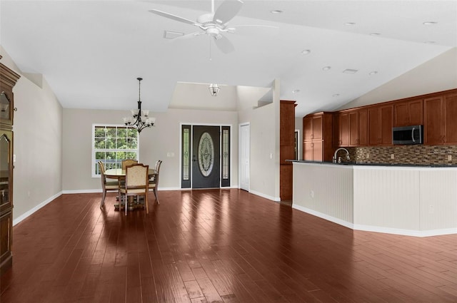 unfurnished dining area with vaulted ceiling, dark hardwood / wood-style floors, ceiling fan with notable chandelier, and sink