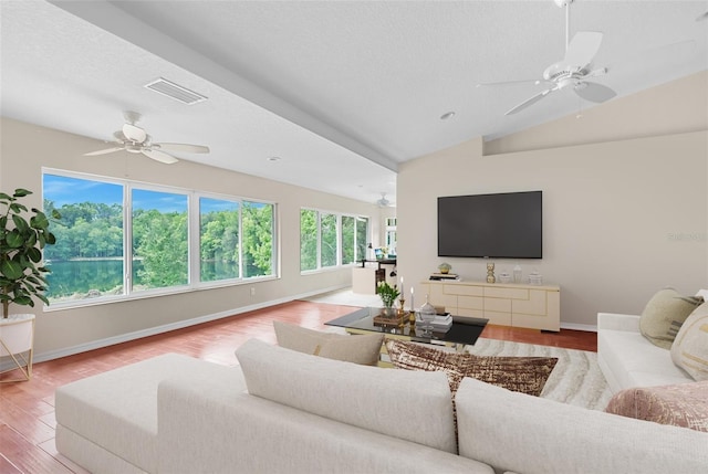 living room with vaulted ceiling, hardwood / wood-style floors, a textured ceiling, and ceiling fan