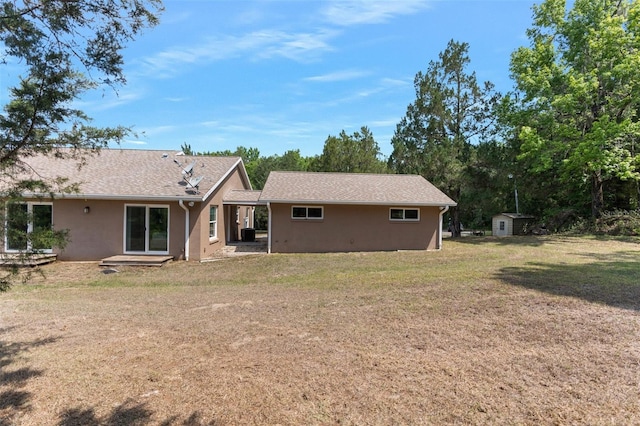 rear view of house with a storage shed and a lawn