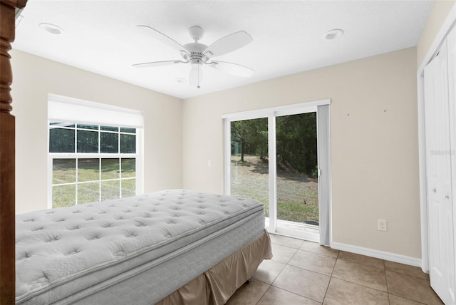 bedroom with ceiling fan, light tile patterned floors, multiple windows, and access to outside