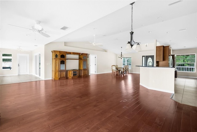 unfurnished living room featuring vaulted ceiling, sink, dark hardwood / wood-style floors, and ceiling fan with notable chandelier