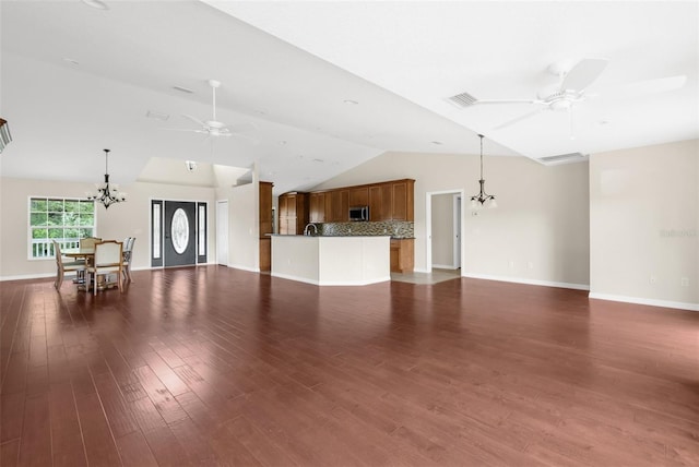 unfurnished living room with dark wood-type flooring, vaulted ceiling, and ceiling fan with notable chandelier