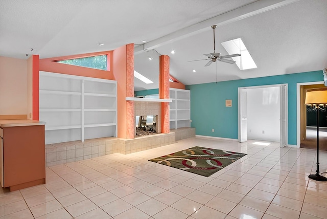 unfurnished living room featuring ceiling fan, light tile flooring, a fireplace, lofted ceiling with skylight, and built in shelves