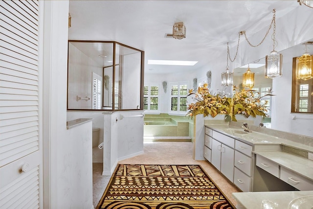 bathroom featuring a skylight, separate shower and tub, and vanity