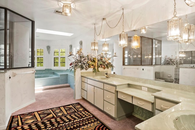 bathroom with a skylight, vanity with extensive cabinet space, toilet, and a tub