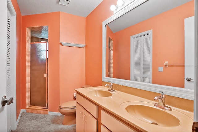 bathroom with toilet, a shower with shower door, double sink, a textured ceiling, and vanity with extensive cabinet space