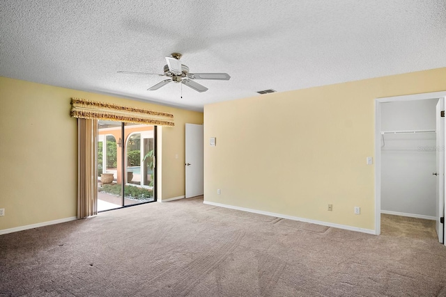 unfurnished bedroom featuring access to exterior, ceiling fan, a spacious closet, light carpet, and a closet