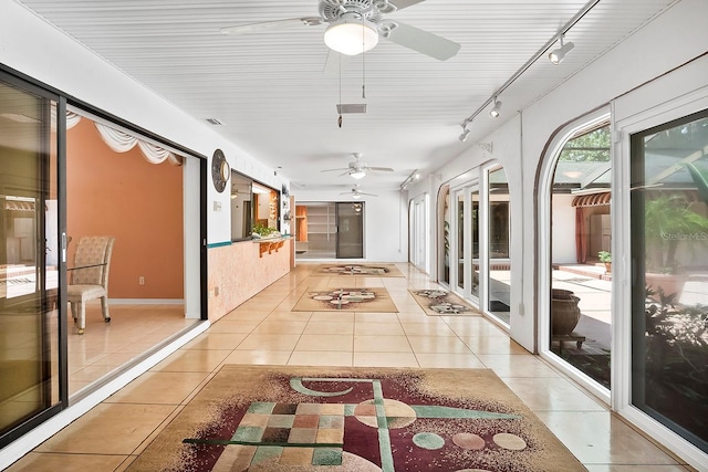 unfurnished sunroom featuring rail lighting and ceiling fan