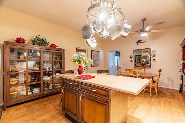 kitchen with a breakfast bar area, ceiling fan, a kitchen island, and light wood-type flooring