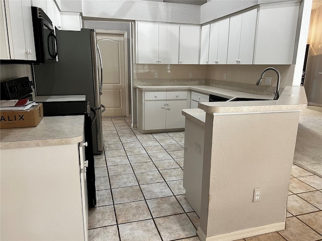 kitchen featuring sink, light tile patterned floors, tasteful backsplash, black appliances, and white cabinets