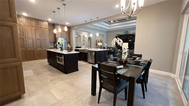 tiled dining room featuring a raised ceiling, a notable chandelier, and sink