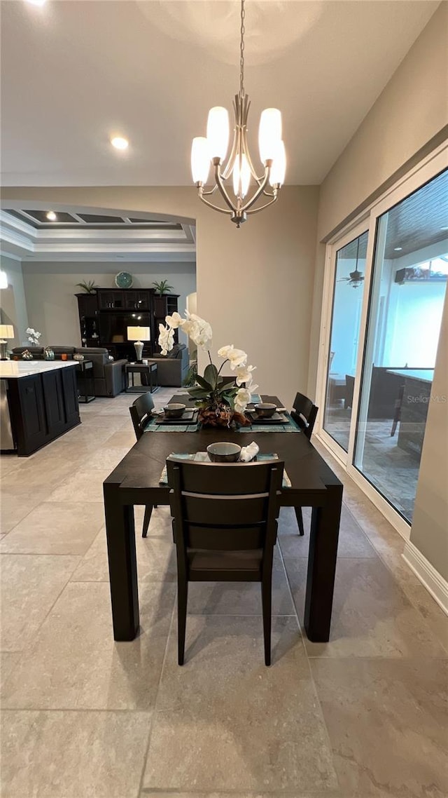 tiled dining room featuring an inviting chandelier and a tray ceiling